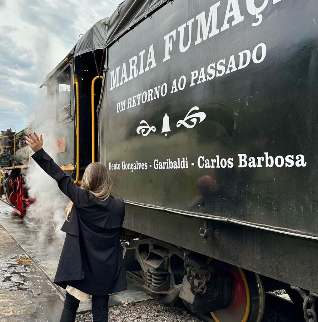 Foto de pessoa ao lado do trem maria fumaça