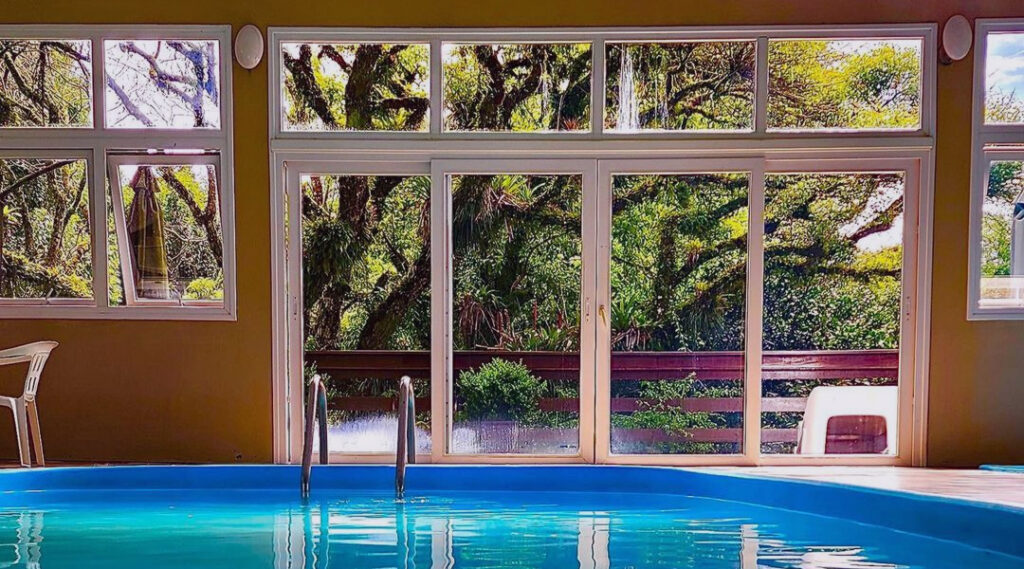 Piscina interna do Hotel Fioreze Quero Quero, pela janela uma árvore no jardim