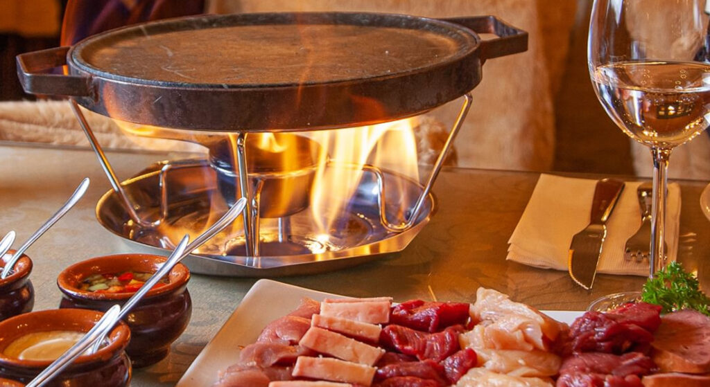 Fondue servido em restaurante típico de Gramado. Chapa com fogo acesa esperando o fondue ser colocado.