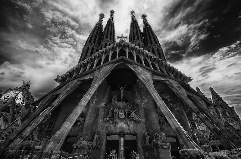 Foto em preto e branco do Templo da Sagrada Família, a foto mostra estátuas nas paredes e 4 torres.