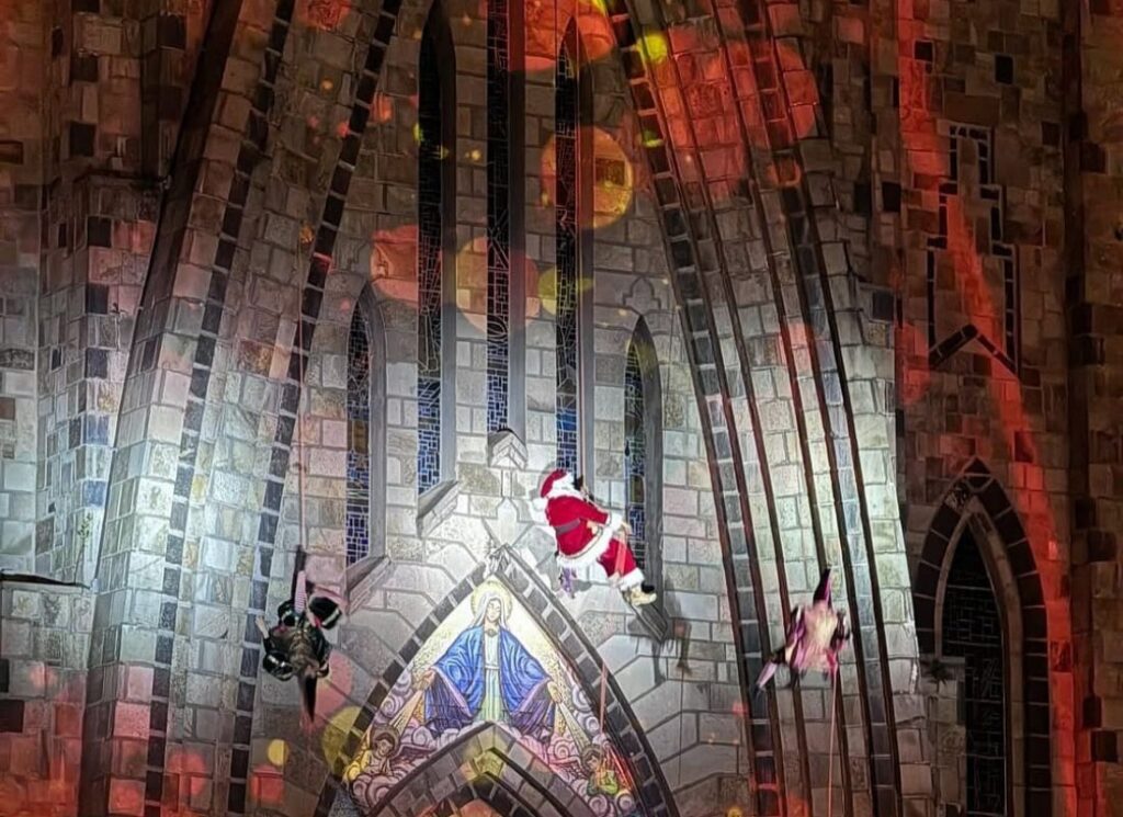 Imagem com foto do Papai Noel descendo pelas paredes da Catedral de Pedra.