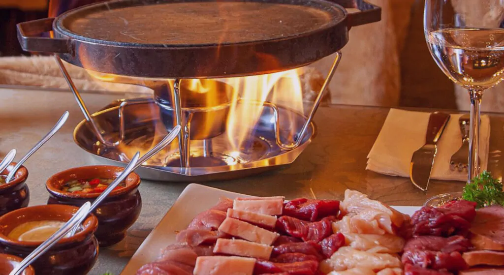 Fondue com carnes ainda esperando para serem assadas e consumidas