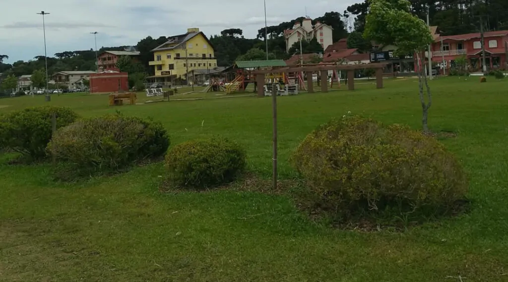 Parque do Lago Canela, foto mostra um pequeno parque com grama verde e casas ao fundo