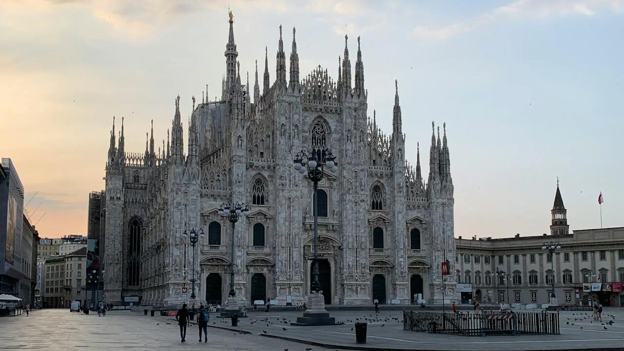 Foto em dia Claro do Duomo di Milano, poucas pessoas andando na praça em frente.