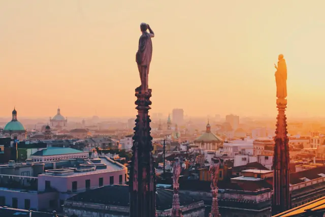 Pico das torres do Duomo de Milano visto sob o por do sol.